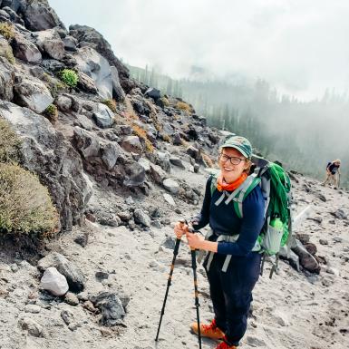 Ginny Moore徒步旅行外面的山上徒步徒步杆，穿着仇恨和背包