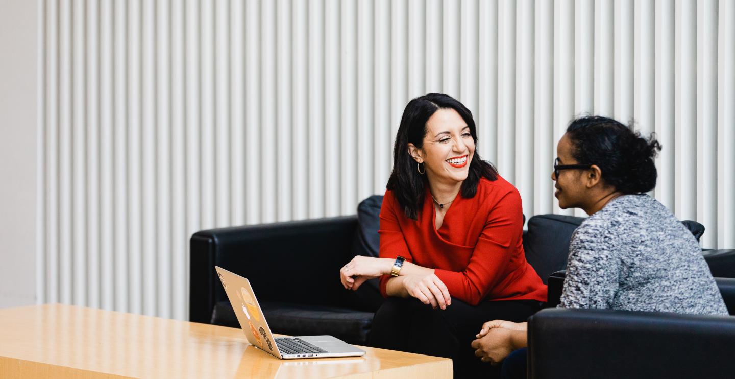 Two women in discussion in front of a laptop